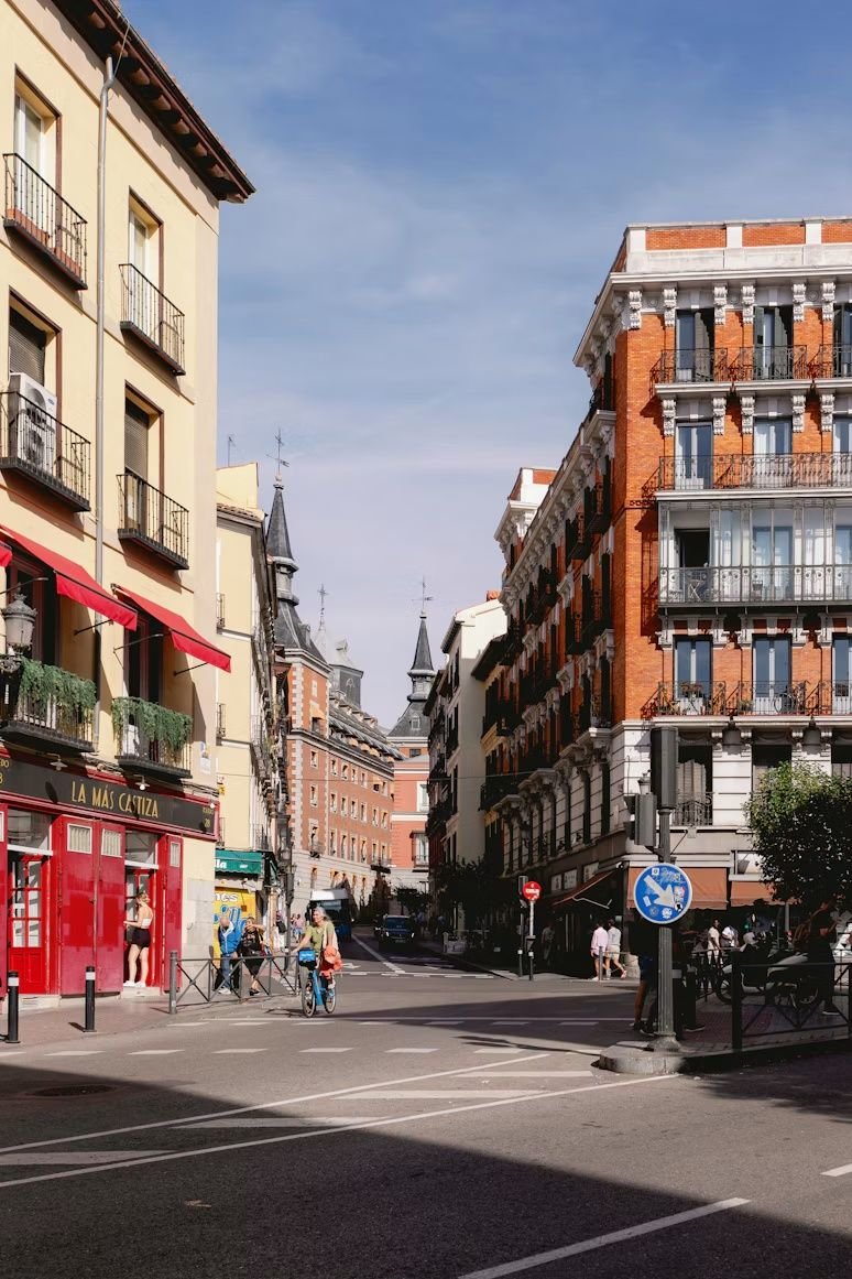 Calle del centro de Madrid con balcones, tiendas y una persona en bicicleta