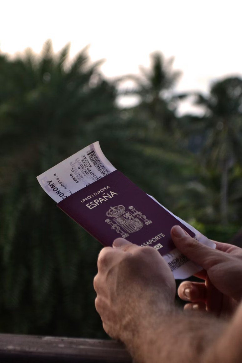 Person signing documents on a wooden table next to a small Spanish flag